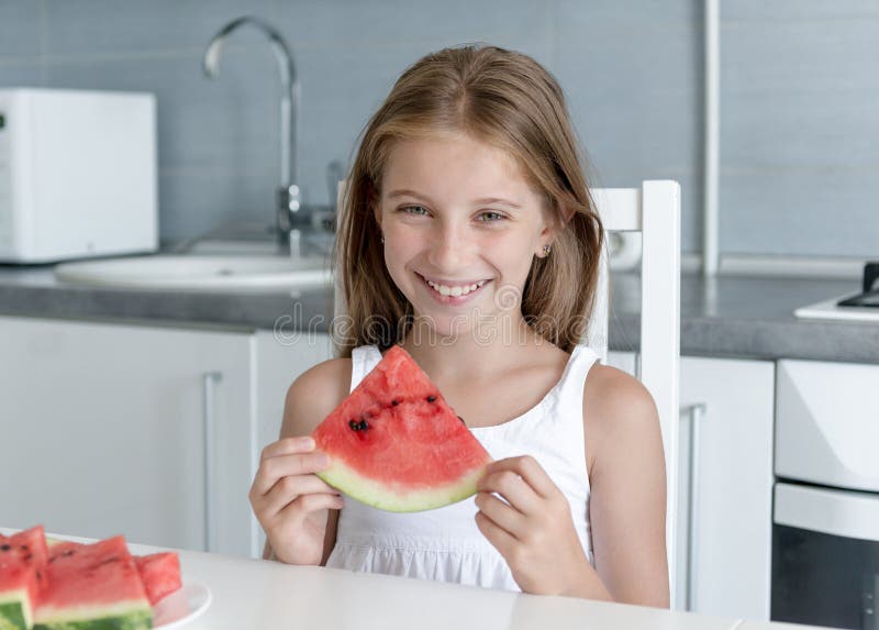 Cute little girl eats a watermelon in the kitchen