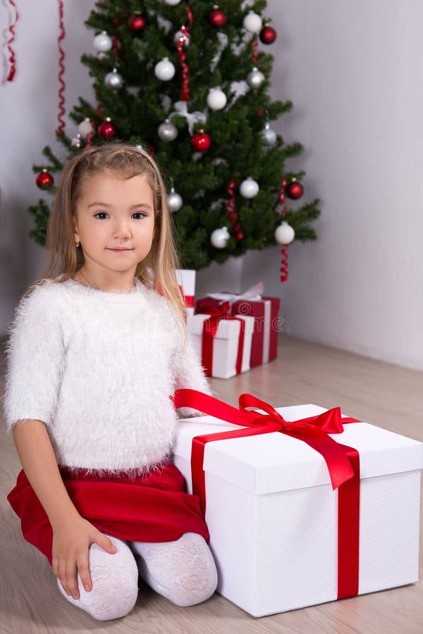 Cute little girl with gift box near Christmas tree at home stock image Cute little girl with gift box near Christmas tree at home stock image