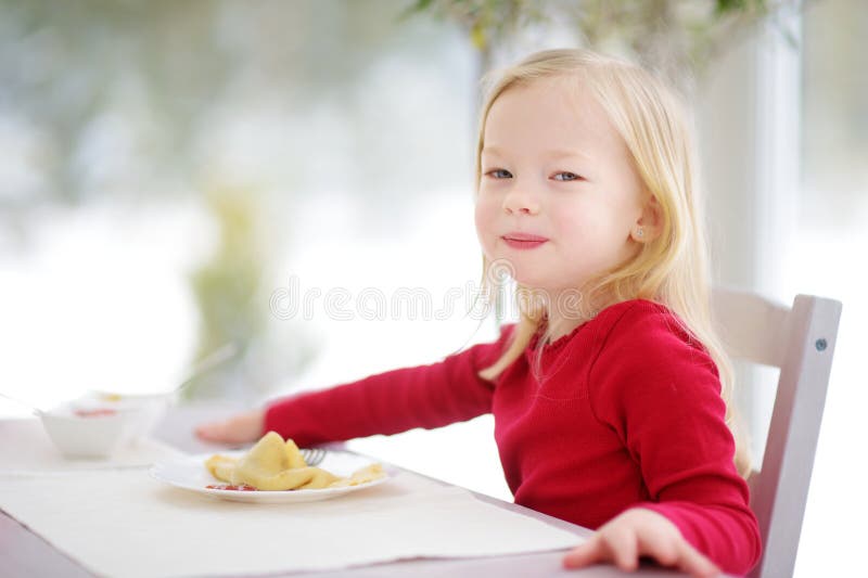 Cute little girl having crepes for breakfast