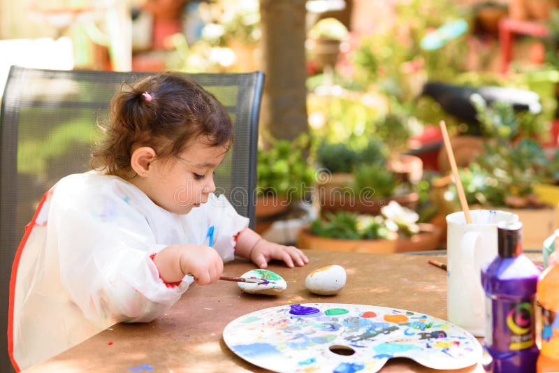 Cute little girl having fun, coloring with brush, writing and painting at summer or autumn garden. royalty free stock photo Cute little girl having fun, coloring with brush, writing and painting at summer or autumn garden. royalty free stock photo
