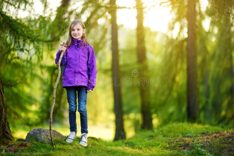 Cute little girl having fun during forest hike on beautiful autumn day in Italian Alps