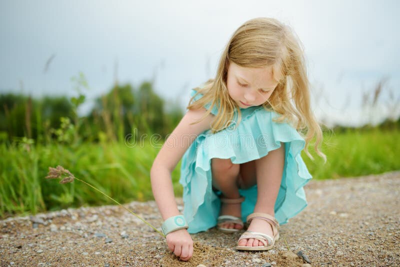 Cute little girl having fun outdoors on sunny summer evening. Child exploring nature