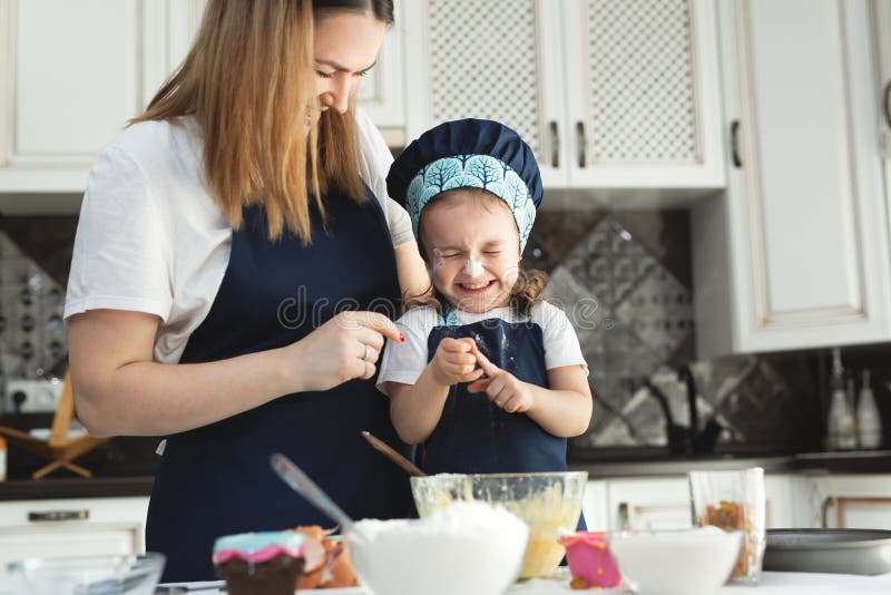 Cute Little Girl and Her Beautiful Mom in Matching Aprons and Caps