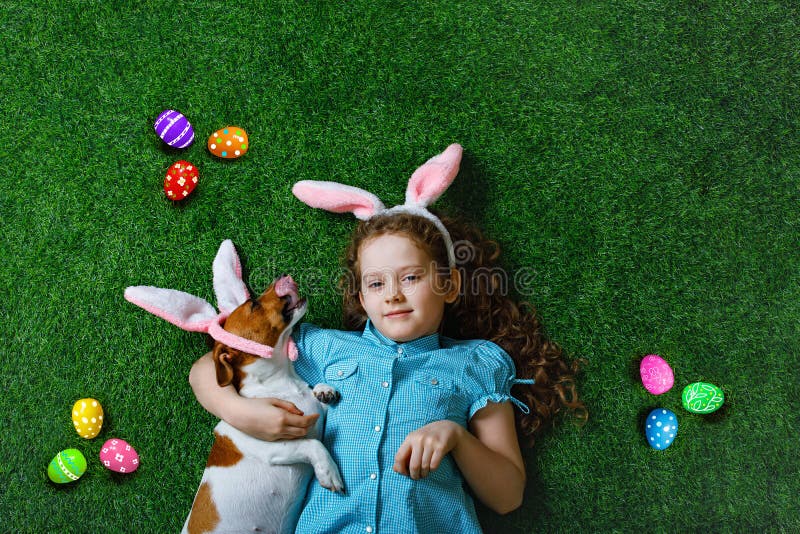 Cute little girl and her dog with rabbit ears lying on green grass royalty free stock images Cute little girl and her dog with rabbit ears lying on green grass royalty free stock images