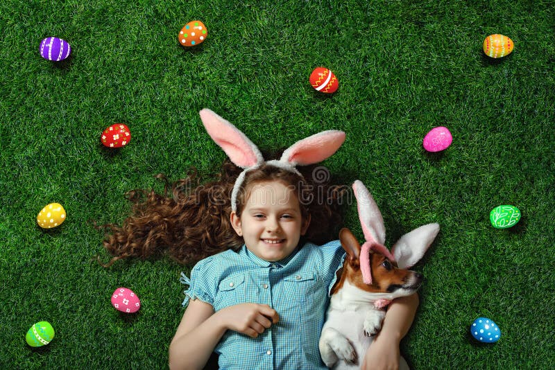 Cute little girl and her dog with rabbit ears lying on green grass. royalty free stock photo Cute little girl and her dog with rabbit ears lying on green grass. royalty free stock photo