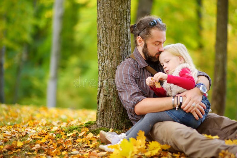 Cute little girl and her father having fun on beautiful autumn day. Happy child playing in autumn park. Kid gathering yellow fall