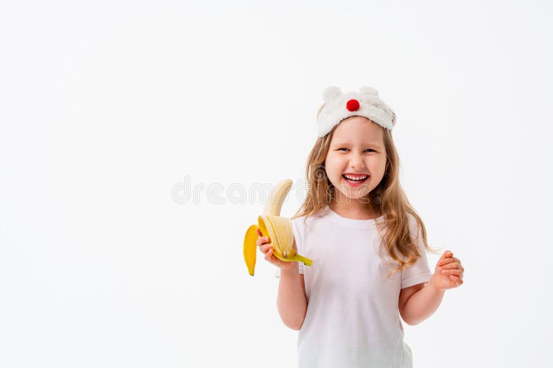 Cute little 4 year old Caucasian girl in casual clothes, holding a banana in her hand, looks very happy, isolated on a white background. The concept of natural nutrition, the benefits of fruit. Cute little 4 year old Caucasian girl in casual clothes, holding a banana in her hand, looks very happy, isolated on a white background. The concept of natural nutrition, the benefits of fruit