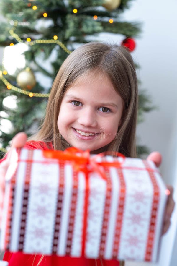 Cute little girl holding gift box at home near Christmas tree. DIY present, holiday concept royalty free stock photos