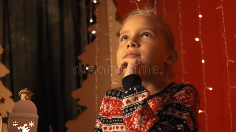 Cute little girl with a lantern writes a letter to Santa Claus on Christmas Eve in slow motion