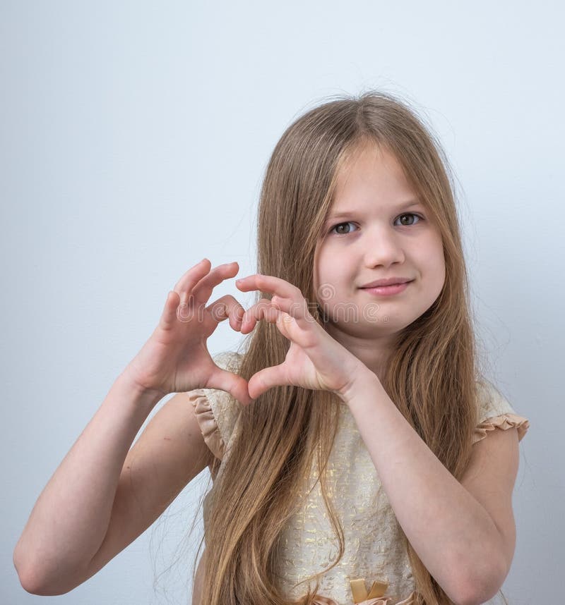 Cute little girl making heart with her hands and smiling on white background. Adorable kid smiling in love showing heart stock images