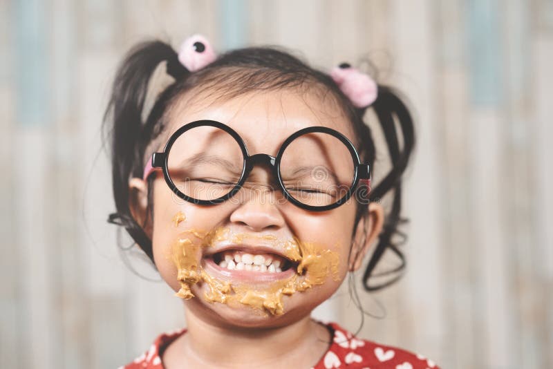 Cute little girl with mouth smeared with peanut butter.