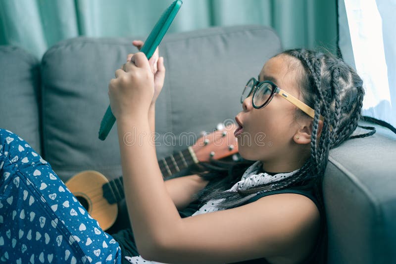 Cute little girl,playing with computer at home laying on sofa