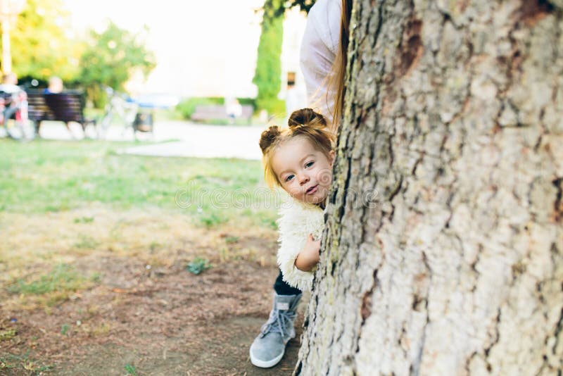 Cute little girl is playing hide and seek outdoors. Cute little girl is playing hide and seek outdoors