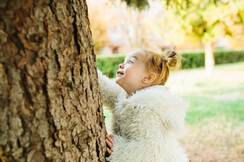 Cute little girl is playing hide and seek outdoors. Cute little girl is playing hide and seek outdoors