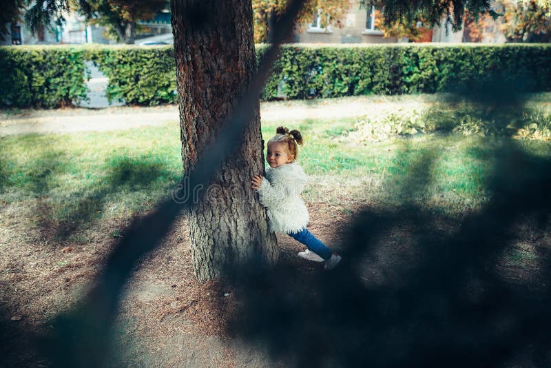 Cute little girl is playing hide and seek outdoors. Cute little girl is playing hide and seek outdoors