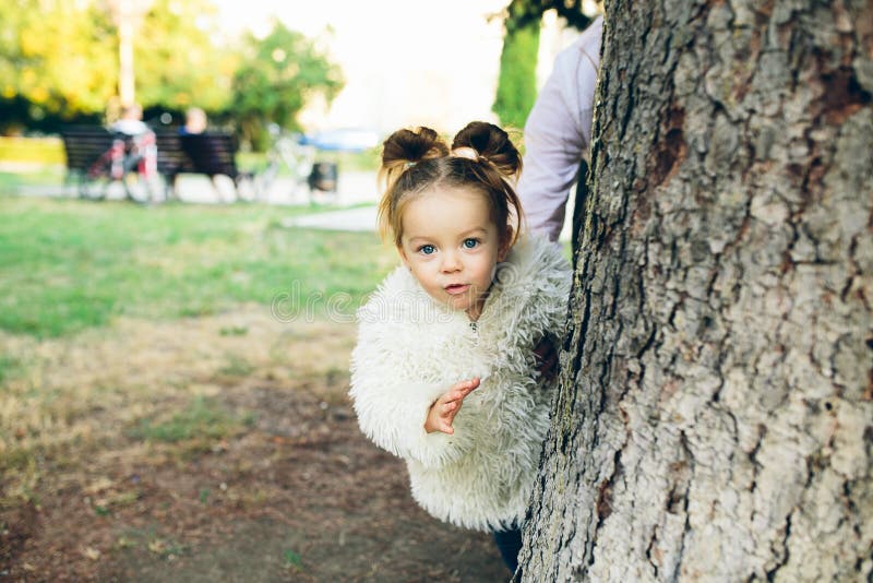 Cute little girl is playing hide and seek outdoors. Cute little girl is playing hide and seek outdoors