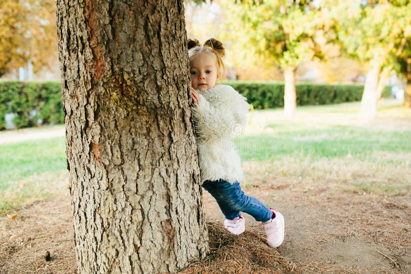 Cute little girl is playing hide and seek outdoors. Cute little girl is playing hide and seek outdoors