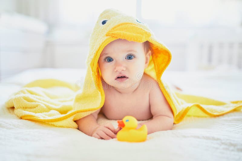 Cute little girl playing with rubber duck after having bath