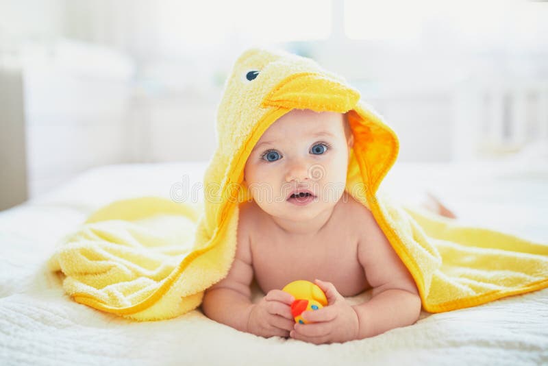 Cute little girl playing with rubber duck after having bath