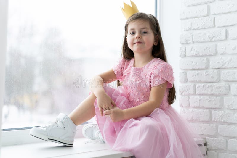 Cute little girl in a princess costume. Pretty child preparing for a costume party. Beautiful queen in gold crown.