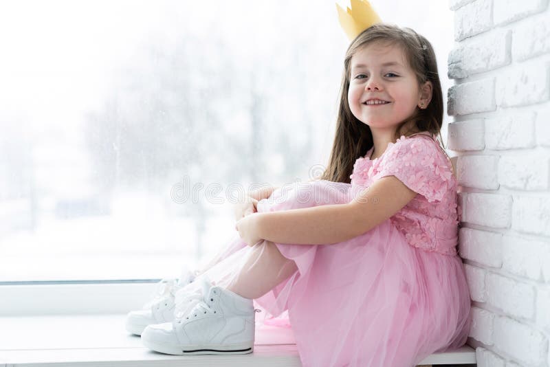 Cute little girl in a princess costume. Pretty child preparing for a costume party. Beautiful queen in gold crown.