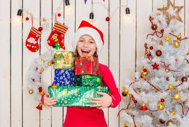 Cute little girl in red hat holding presents