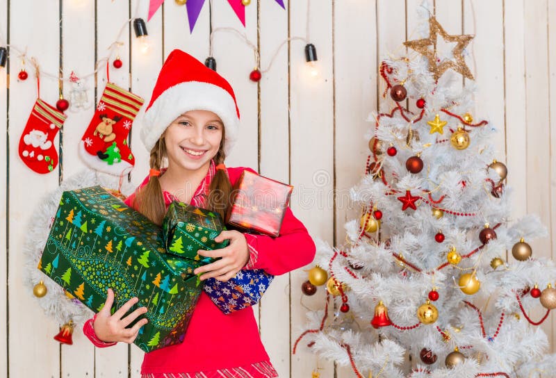 Cute little girl in red hat holding presents