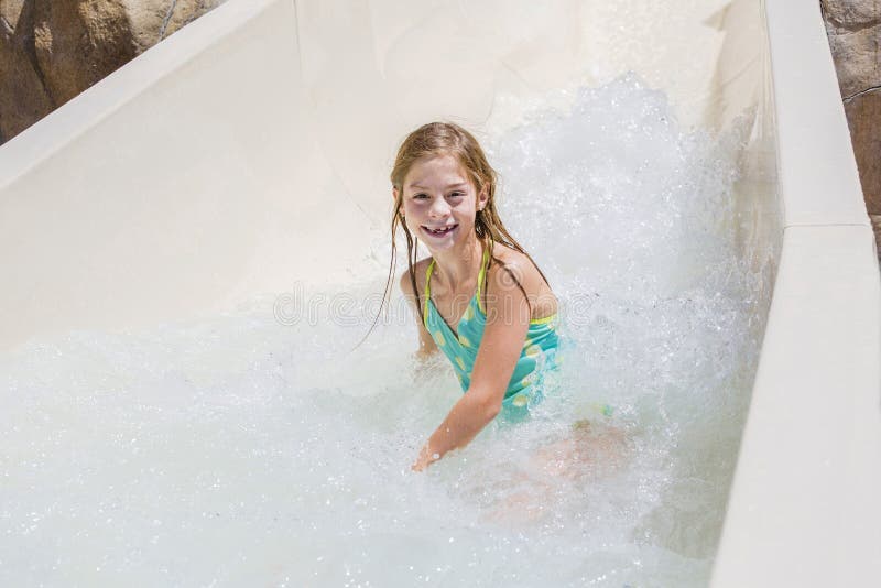 Cute little girl riding down a water slide at a water park