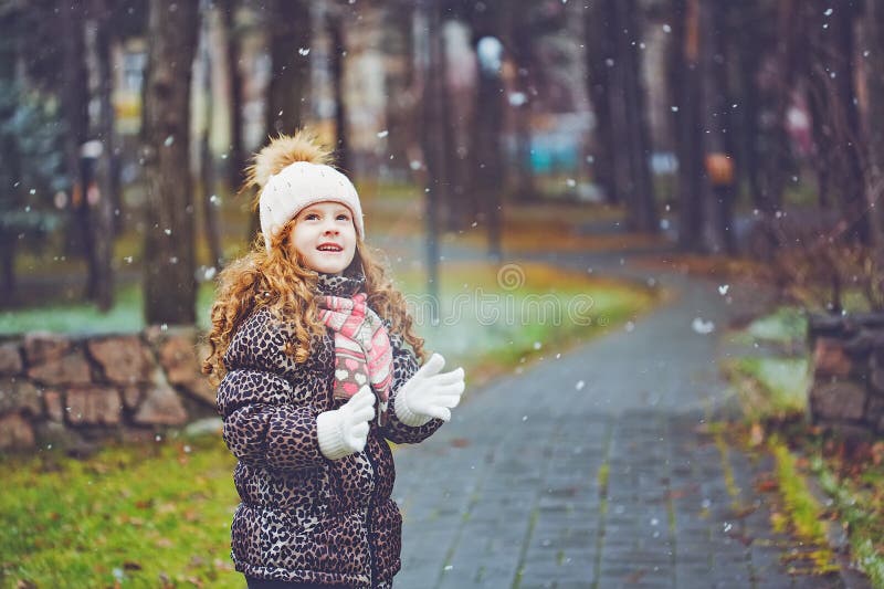 Cute little girl stretches her hand to catch falling snowflakes. stock photos Cute little girl stretches her hand to catch falling snowflakes. stock photos