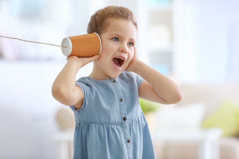 Cute little girl using plastic cup as telephone while playing at home stock images Cute little girl using plastic cup as telephone while playing at home stock images