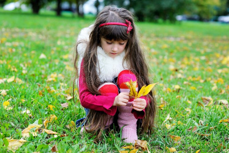 Cute little girl wearing fur coat in autumn forest