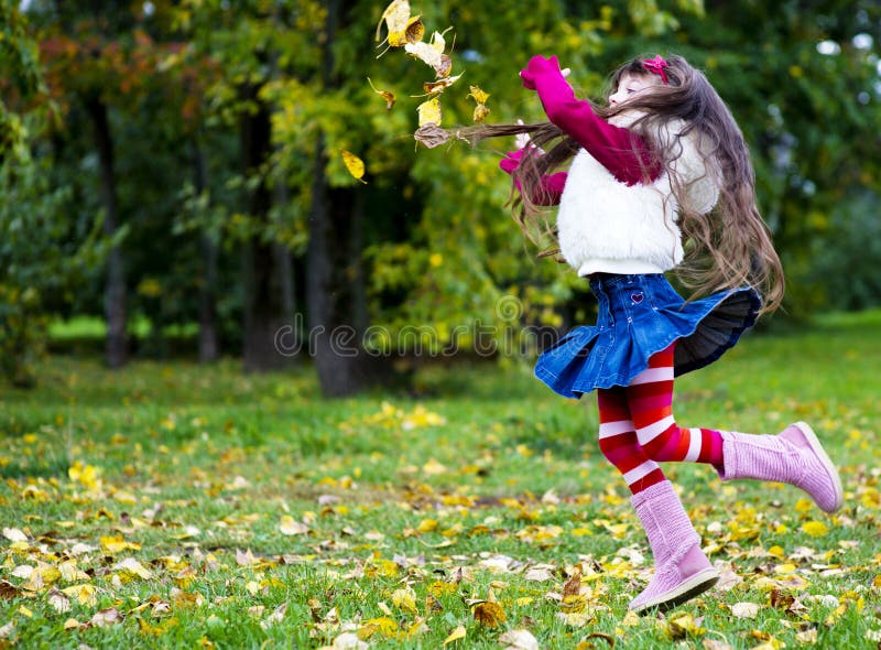 Cute little girl wearing fur coat in autumn forest