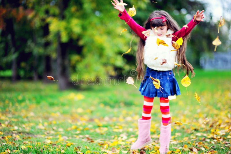 Cute little girl wearing fur coat in autumn forest