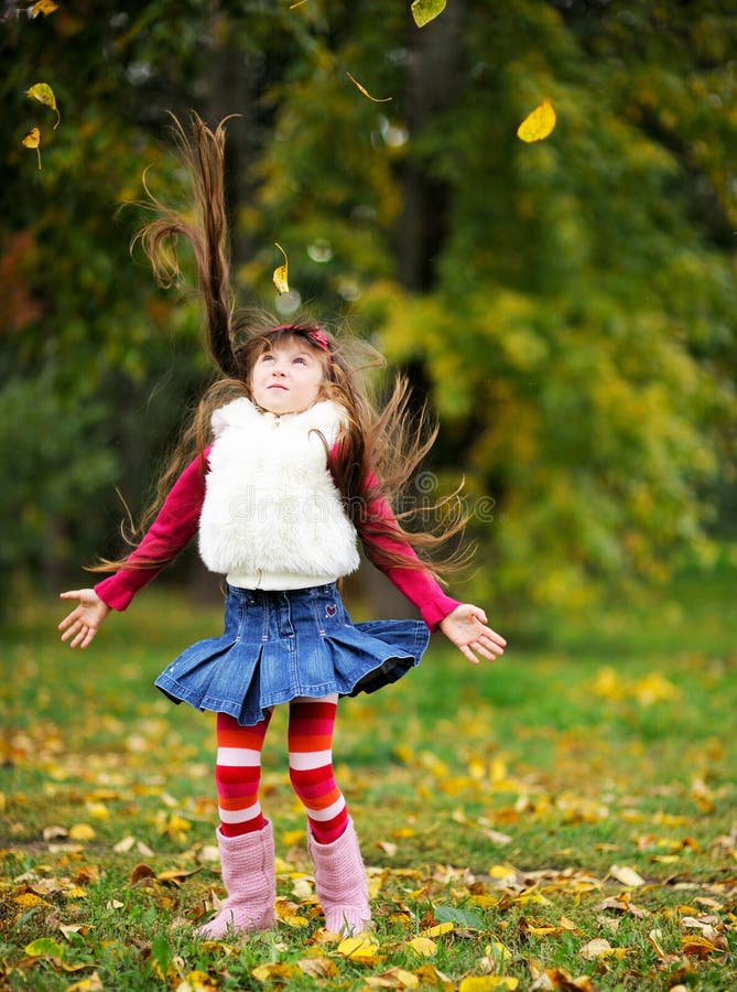 Cute little girl wearing fur coat in autumn forest