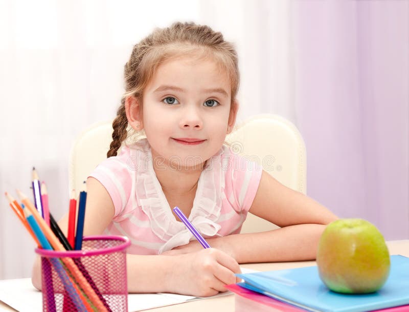 Cute little girl is writing at the desk