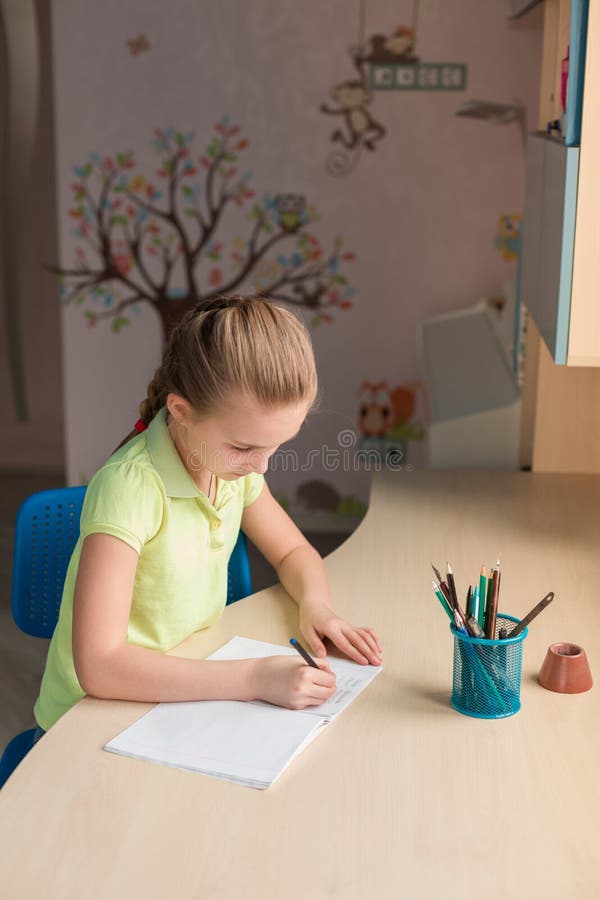 Cute Little Girl Writing Her Homework at the Table Stock Photo Image