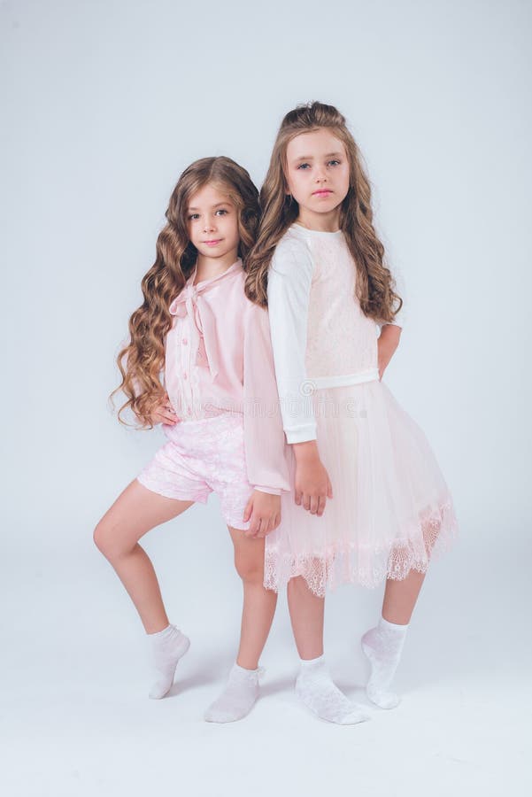 Cute little girls with curly hair in fashionable clothes of white and pink stock image Cute little girls with curly hair in fashionable clothes of white and pink stock image