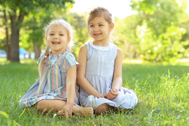 Cute Little Girls Sitting on Green Grass Stock Photo - Image of girls ...