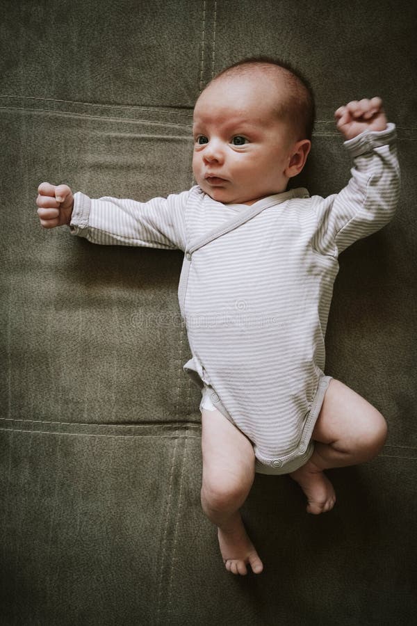 Cute little newborn baby wearing bodysuit lying on back. stock photo