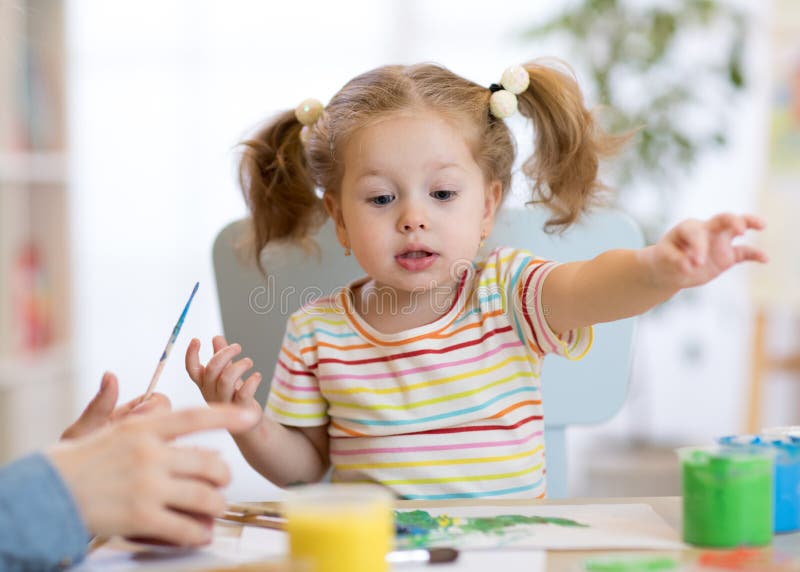Cute little toddler girl in striped shirt and pony tails paints in the art class royalty free stock photos Cute little toddler girl in striped shirt and pony tails paints in the art class royalty free stock photos