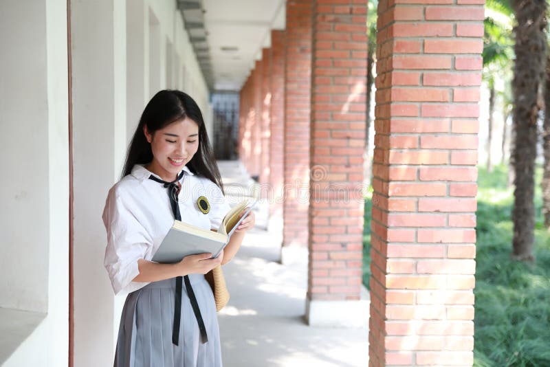 Cute lovely Asian Chinese pretty girl wear student suit in school in class enjoy free time smile and reading book