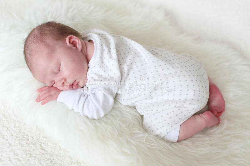 Cute newborn girl sleeps on fur plaid