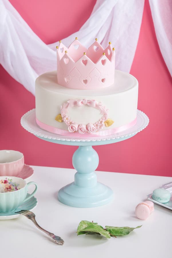 Cute pink cake with a crown on the table to the birthday for a Princess. Baby, child.