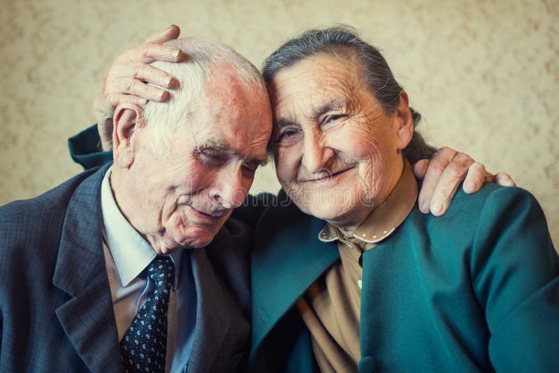 Cute 80 plus year old married couple posing for a portrait in their house. Love forever concept