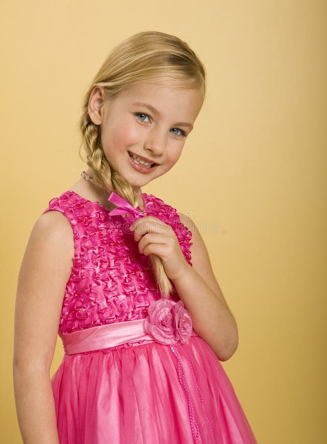 Carino cinque anni ragazza in un abito rosa da principessa, con lo sfondo giallo.