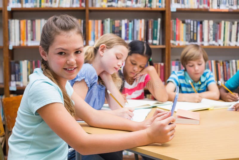 Cute pupil using tablet computer in library stock image Cute pupil using tablet computer in library stock image