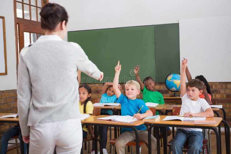 Cute pupils raising their hands in class stock images