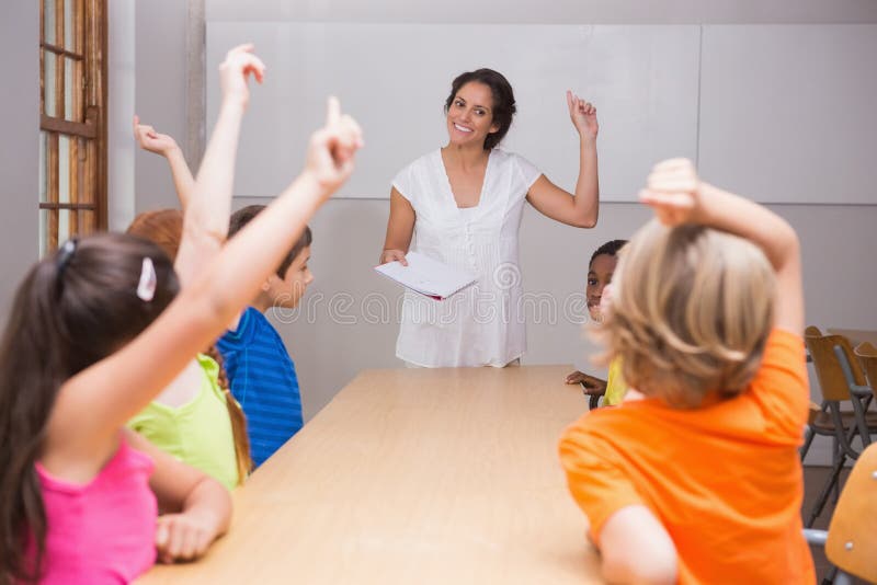 Cute pupils raising their hands in class royalty free stock image