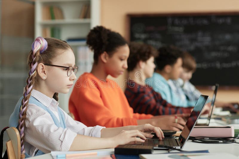 Cute schooolgirl using computers in row in school classroom royalty free stock photos