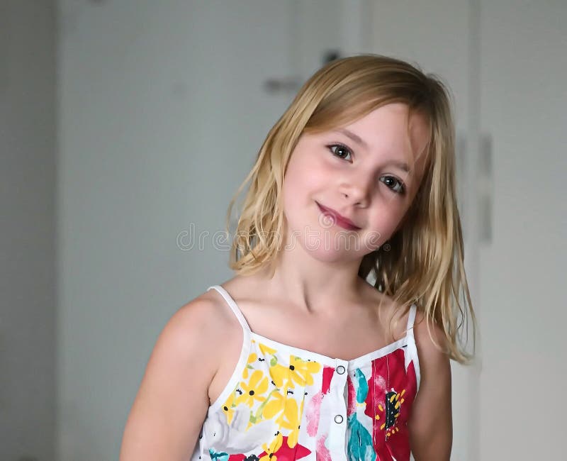 Six Year Old Blonde Girl In A Summer White Dress With Flowers Smiling